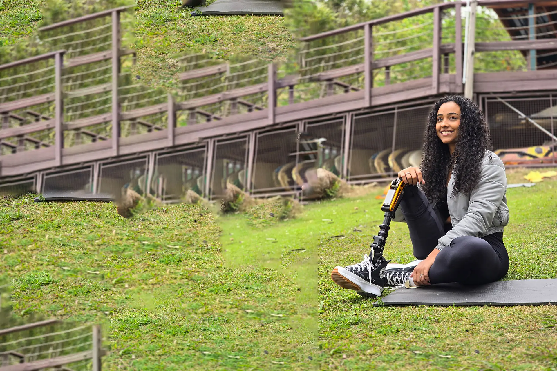 Smiling woman sitting on a lawn, with a leg prosthesis and sneakers